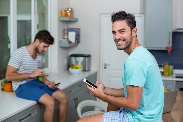 Portrait of smiling man using phone with friend 