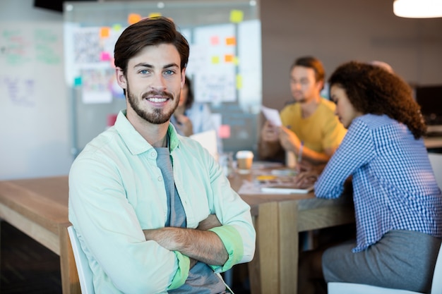 Portrait of smiling man with arms crossed in office