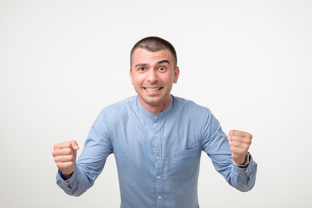 Portrait Of Smiling Man With The Fists Up Against A White Background