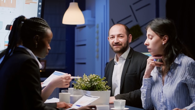 Portrait of smiling manager man looking into camera working at company strategy in meeting office room late at night