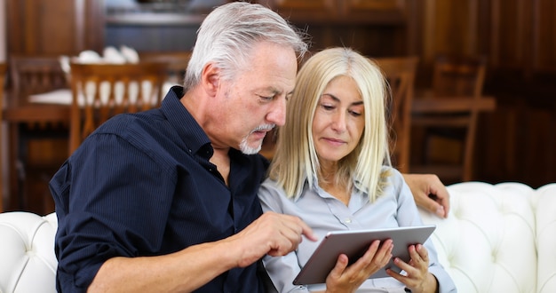 Portrait of a smiling mature couple using digital tablet on sofa at home