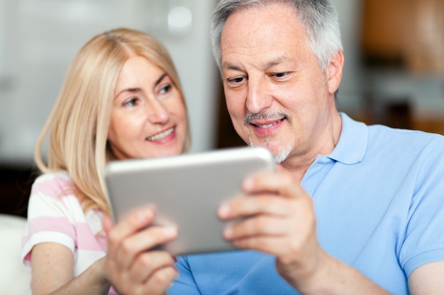 Portrait of a smiling mature couple using digital tablet on sofa at home