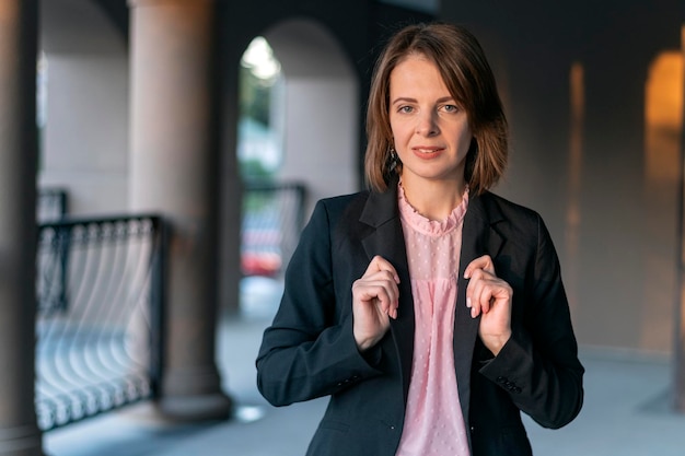 Portrait of smiling middleaged woman in pink blouse and jacket outside Business girl with bob haircut