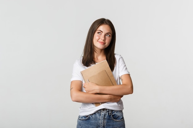 Portrait of smiling nostalgic female student looking upper left corner