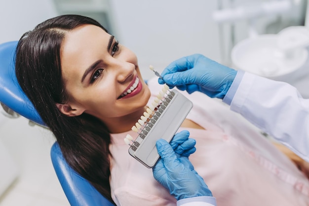 Portrait of smiling patient in dentist chair choosing tooth implants at the clinic