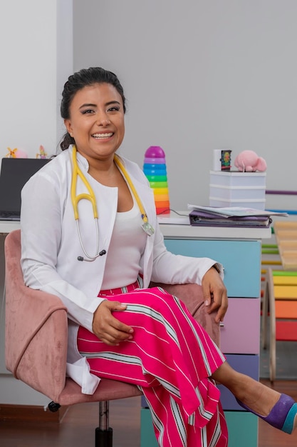 Portrait of a smiling pediatrician doctor sitting at the desk in her office