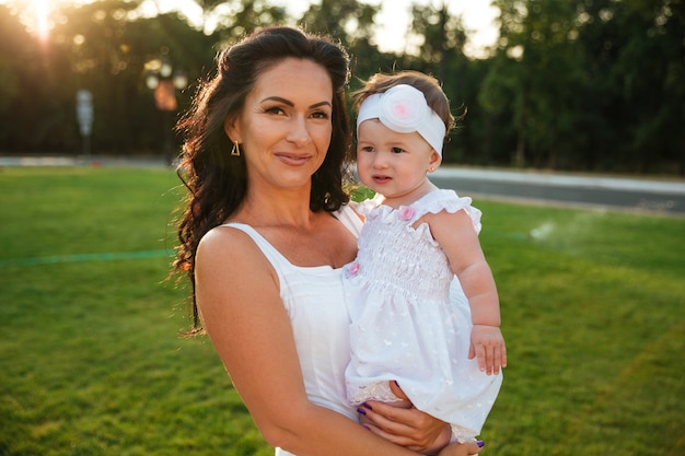 Portrait of smiling pretty mother with her little daughter in park