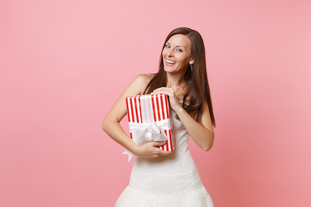 Portrait of smiling pretty woman in beautiful white dress holding red box with gift present