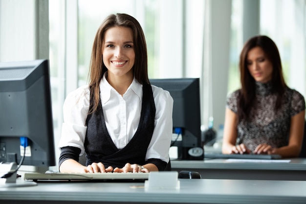 Portrait of smiling pretty young business woman sitting on workplace