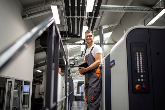 Portrait of smiling printer standing by printing machine in print house.