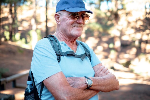 Portrait of smiling senior caucasian man standing in the woods ready for mountain excursion