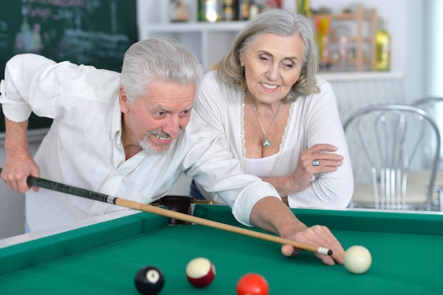 Portrait of smiling senior couple playing billiard together