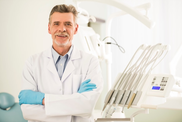 Photo portrait of a smiling senior dentist in dental clinic.