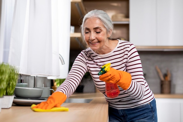 Portrait Of Smiling Senior Woman Making Cleaning In Kitchen