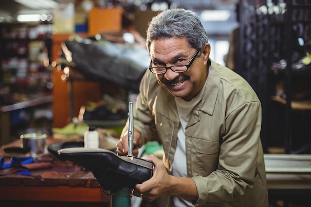 Portrait of smiling shoemaker hammering on a shoe