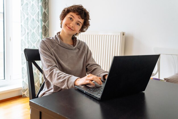 Portrait smiling teenage girl using laptop at home