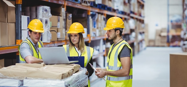 Portrait of smiling warehouse managers using laptop