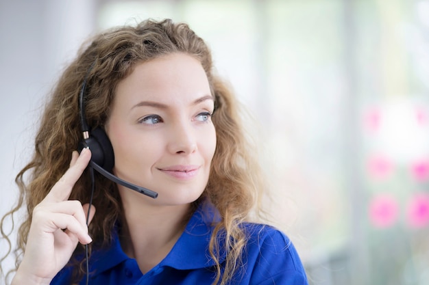 Portrait of smiling woman in blue shirt working with headset.