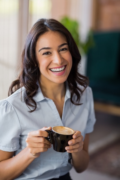 Portrait of smiling woman having cup of coffee