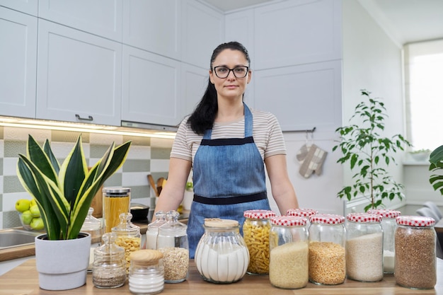 Portrait of smiling woman housewife in an apron in kitchen