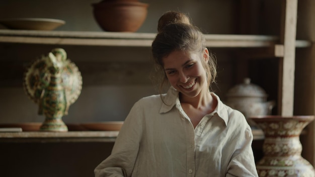 Portrait of smiling woman posing in workshop Closeup happy artist doing craft in pottery Excited ceramist making clay product in studio Attractive girl looking at camera