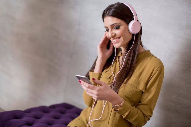 Portrait of smiling woman sitting and listening to music on headset