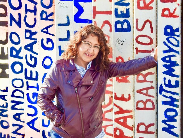 Photo portrait of smiling woman standing against text on wall