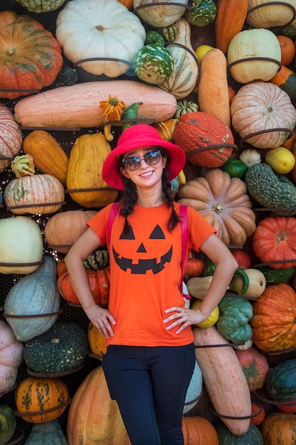 Portrait of smiling woman standing by pumpkins