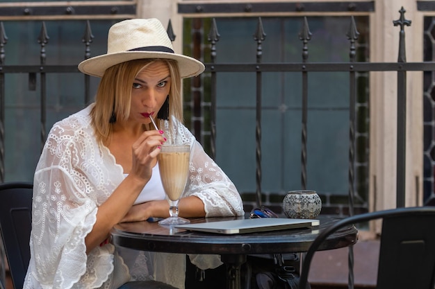 Photo portrait of smiling woman with coffee sitting at outdoor cafe