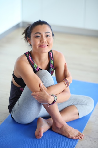 Portrait of smiling yoga woman sitting at yoga mat after workout at yoga studio Yoga Woman