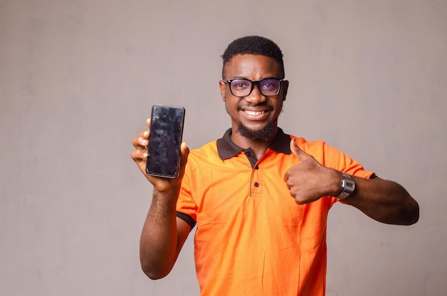 Portrait of a smiling young afro american man dressed in casual isolated pointing at blank screen mobile phone