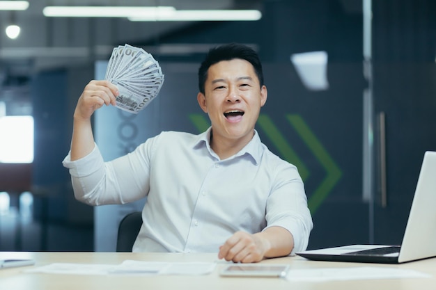 Portrait of a smiling young asian man businessman sitting in the office in front of the camera and