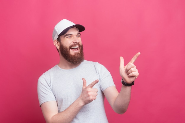 Portrait of smiling young bearded man pointing away