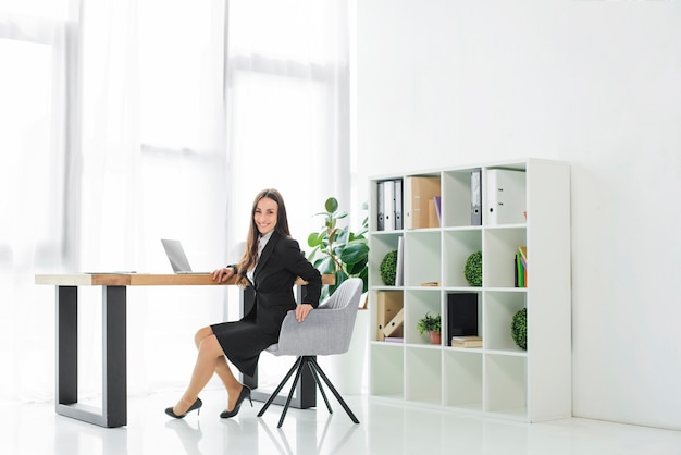 Portrait of a smiling young businesswoman sitting on chair looking at camera