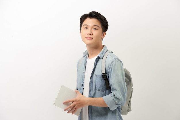 Portrait of smiling young college student with books and backpack against white background