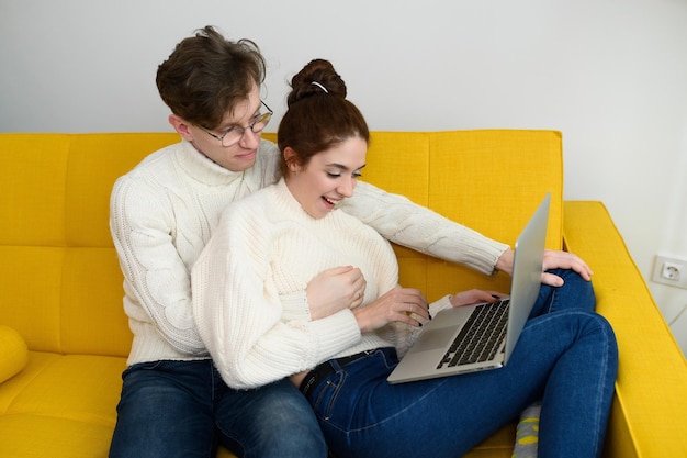 Portrait of a smiling young couple using laptop at home indoor high quality photo