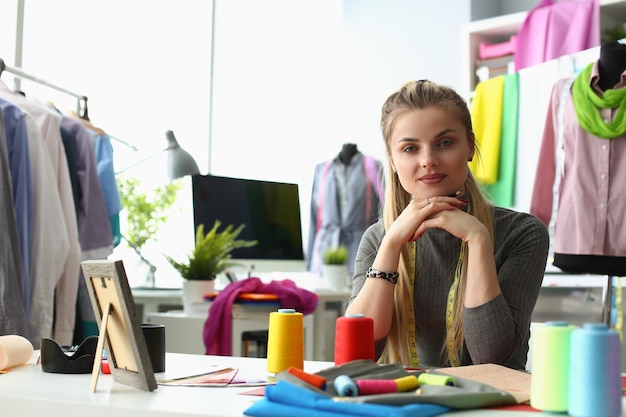 Portrait of smiling young dressmaker or tailor sewing fabric creates new clothes in own workshop