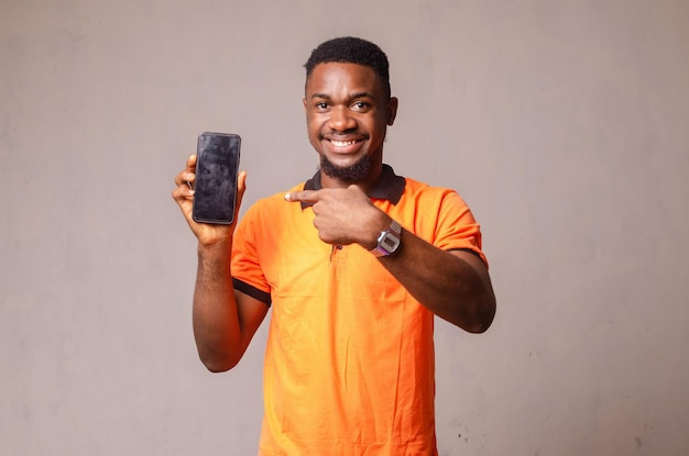 Portrait Of Smiling Young Man Using Mobile Phone While Standing Against White Background