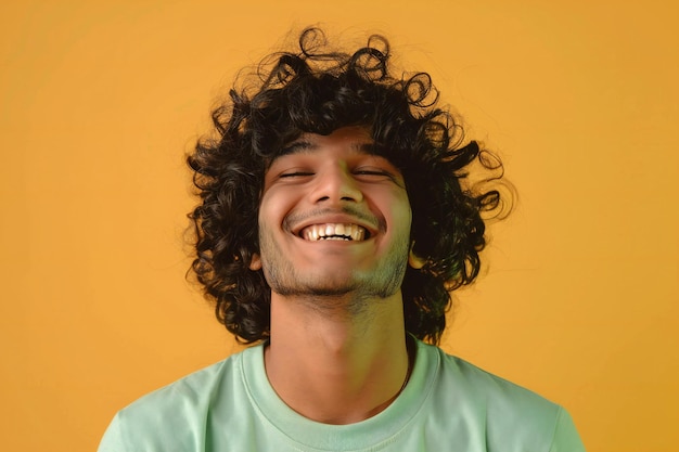 Portrait of a smiling young man with curly hair on yellow background