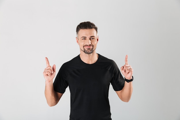 Portrait of a smiling young sportsman pointing fingers up