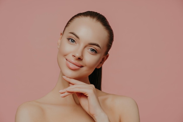 Photo portrait of smiling young woman against pink background