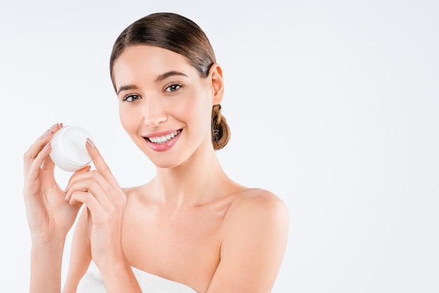 Portrait of smiling young woman holding cream posing isolated over white background