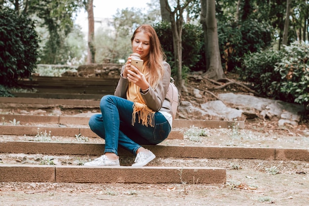 Photo portrait of a smiling young woman sitting on staircase