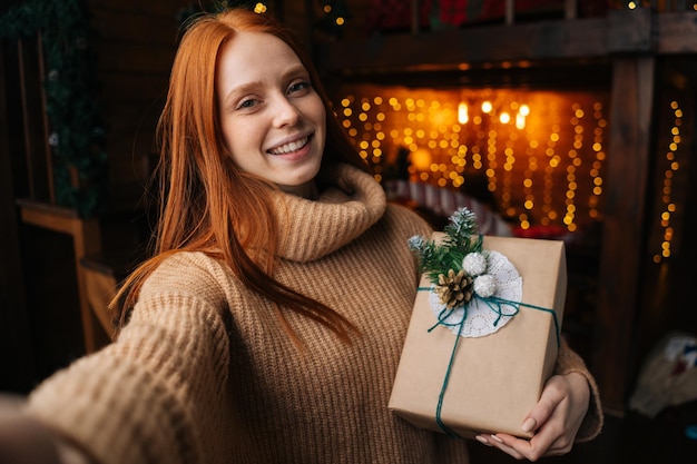 Portrait of smiling young woman thanking boyfriend for box with Christmas present looking at camera