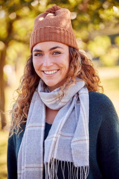 Portrait Of Smiling Young Woman Wearing Hat And Scarf In Autumn Park