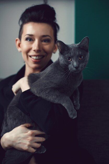 Photo portrait of smiling young woman with cat against black background