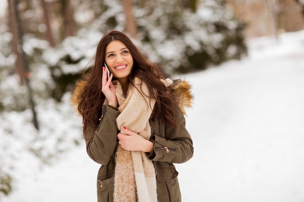 Portrait of smiling young woman with cell phone in winter outdoors