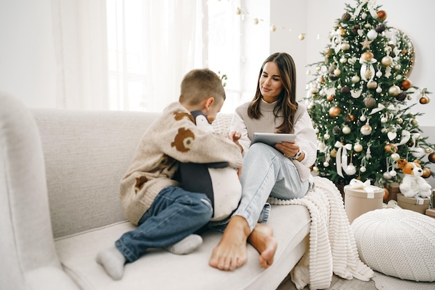 Portrait of a smiling young woman with her son using digital tablet on winter holidays