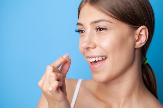 Portrait of smiling young woman with Omega 3 fish oil capsule