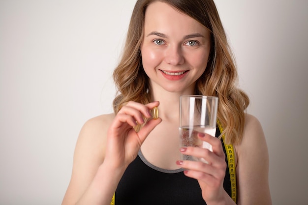 Portrait of smiling young woman with Omega 3 fish oil capsule